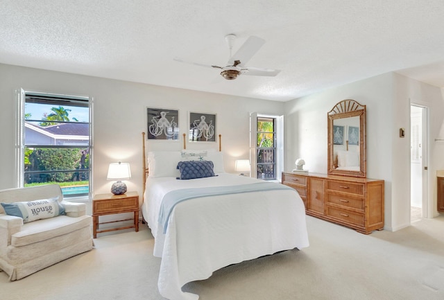 bedroom with ceiling fan, light carpet, and a textured ceiling