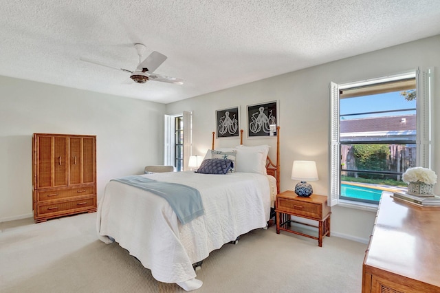 bedroom featuring ceiling fan, light colored carpet, and a textured ceiling