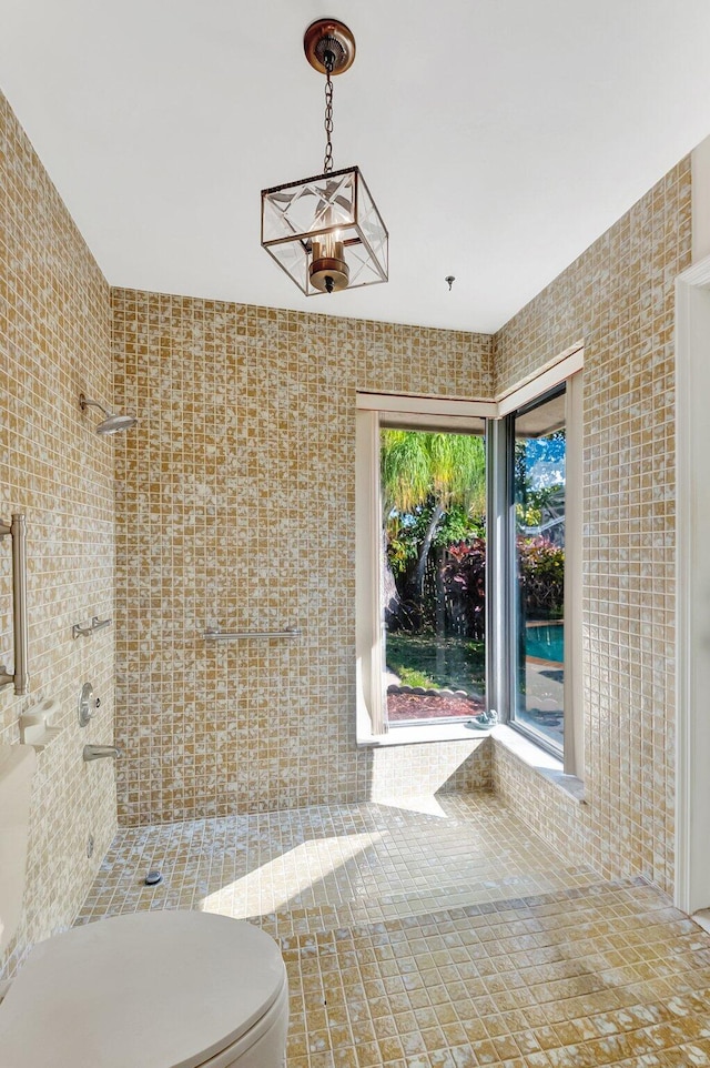 bathroom featuring a tile shower, toilet, and tile walls