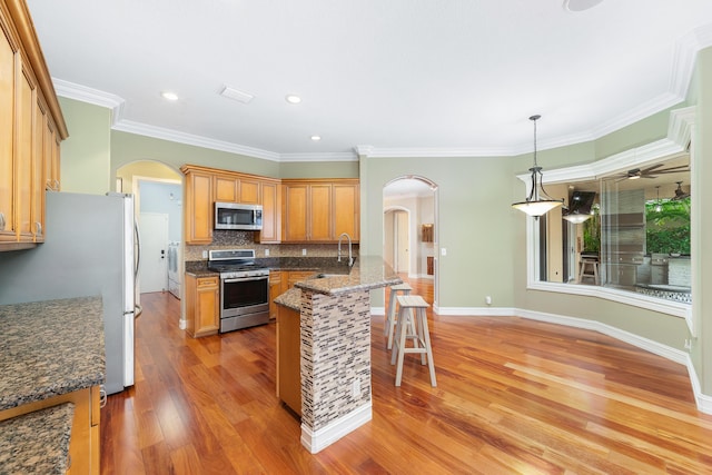 kitchen with a breakfast bar, ornamental molding, decorative light fixtures, washer / dryer, and stainless steel appliances