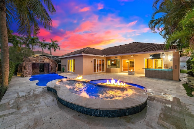 view of swimming pool with ceiling fan, a patio, an outdoor stone fireplace, and an outdoor fire pit