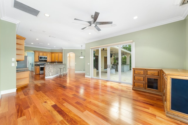 unfurnished living room with light hardwood / wood-style floors, ceiling fan, and ornamental molding