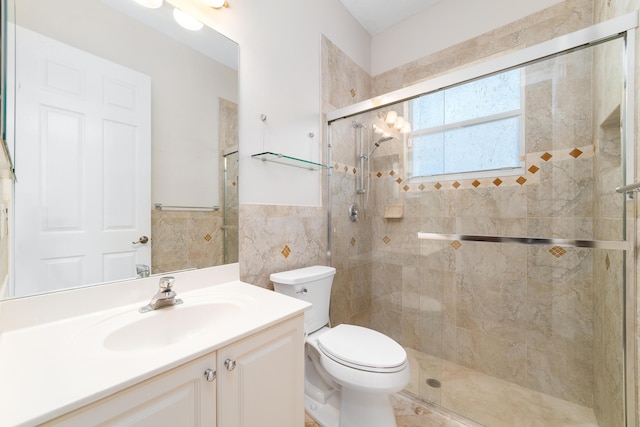 bathroom with vanity, a shower with door, toilet, and tile walls