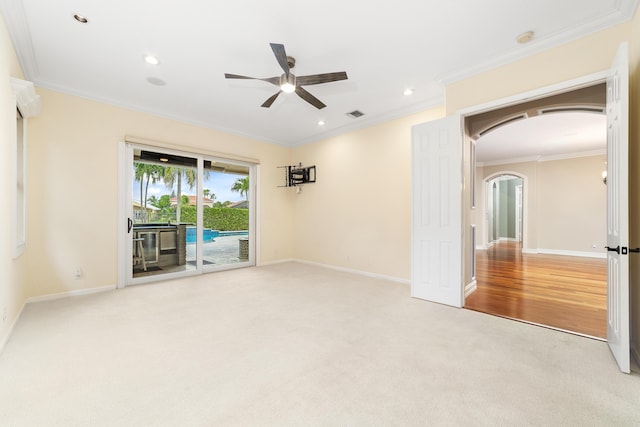 carpeted spare room with ceiling fan and crown molding