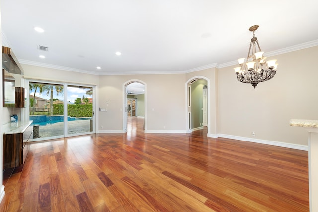 unfurnished living room featuring hardwood / wood-style flooring, ornamental molding, and an inviting chandelier