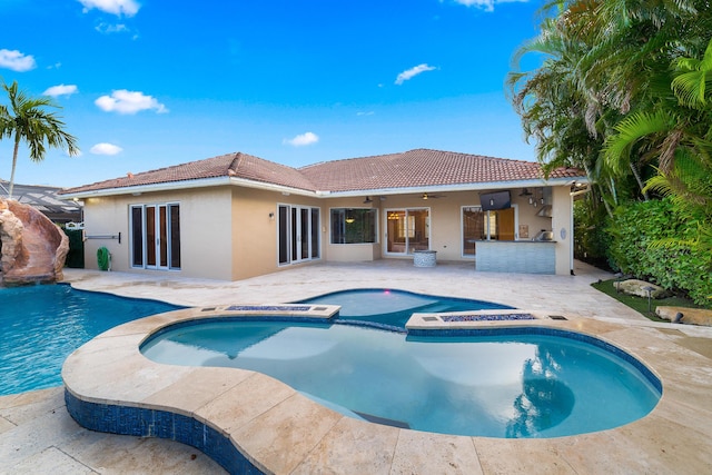 view of swimming pool with ceiling fan, a patio area, an outdoor bar, and an in ground hot tub