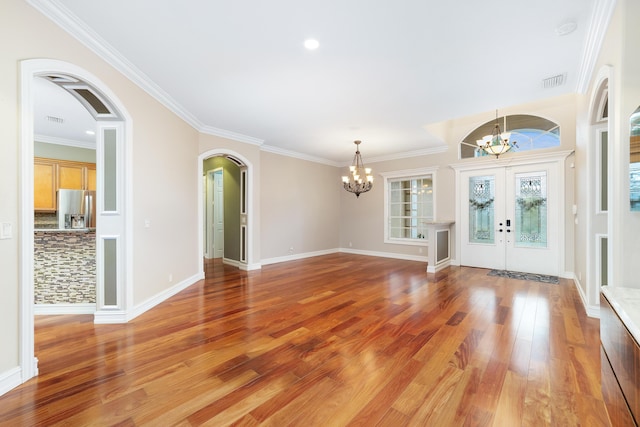 entrance foyer with french doors, ornamental molding, a notable chandelier, and hardwood / wood-style floors