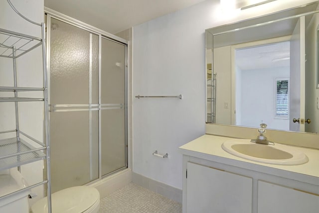 bathroom featuring tile patterned flooring, vanity, a shower with shower door, and toilet