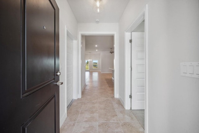 hall featuring a textured ceiling and light tile patterned flooring