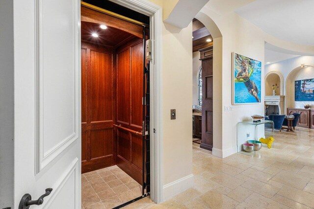 791 NE Marine Dr, Boca Raton, FL 33431 - hallway with arched walkways, elevator, stone tile flooring, and baseboards
