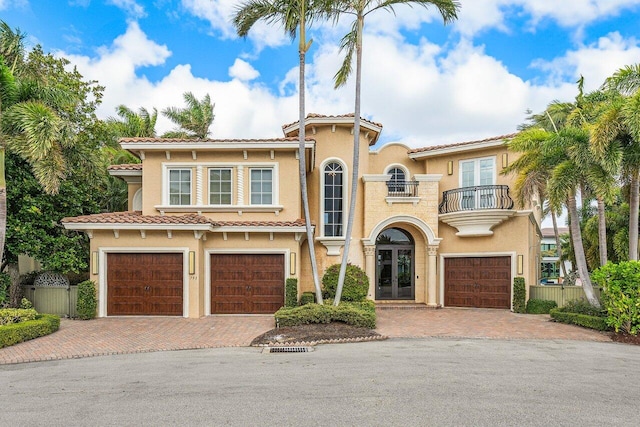 mediterranean / spanish house featuring a garage, a balcony, and french doors