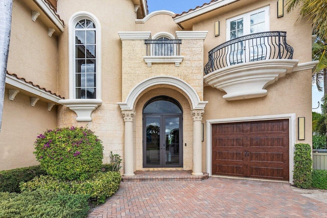 doorway to property with a balcony, french doors, and a garage