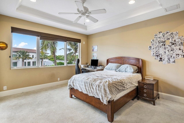 bedroom featuring a raised ceiling, ceiling fan, crown molding, and light colored carpet