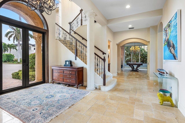 791 NE Marine Dr, Boca Raton, FL 33431 - entryway featuring arched walkways, a chandelier, stone tile floors, a high ceiling, and stairway