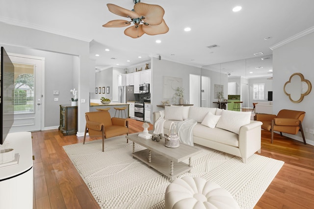 living room featuring ornamental molding, ceiling fan, and light wood-type flooring