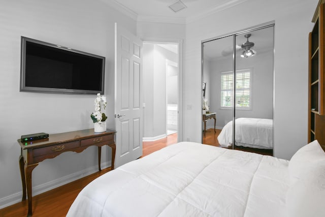 bedroom featuring wood-type flooring, ornamental molding, and a closet