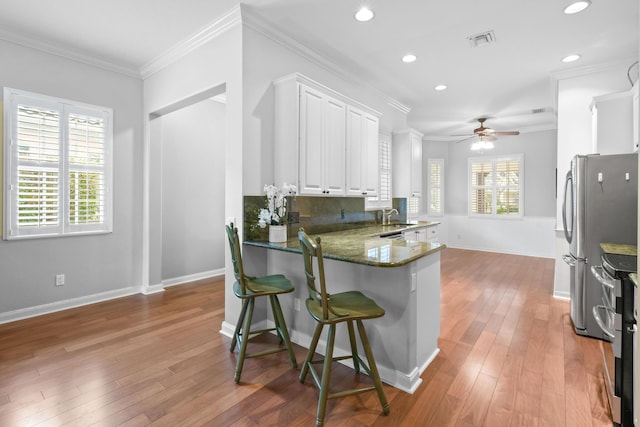 kitchen featuring a wealth of natural light, white cabinets, ceiling fan, and kitchen peninsula