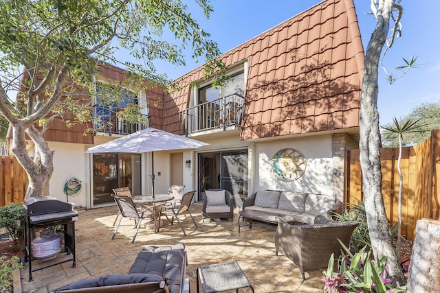 rear view of property featuring outdoor lounge area, a patio area, and a balcony