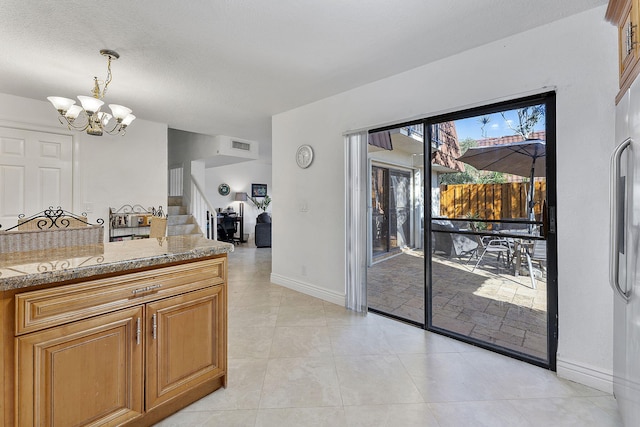 kitchen featuring a textured ceiling, light tile patterned floors, decorative light fixtures, and a notable chandelier