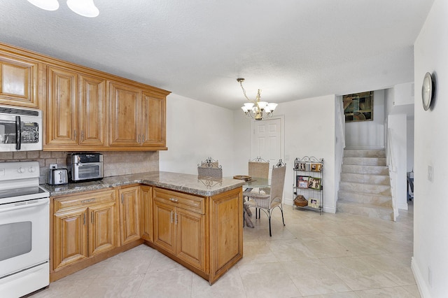 kitchen featuring kitchen peninsula, a chandelier, dark stone countertops, and electric stove