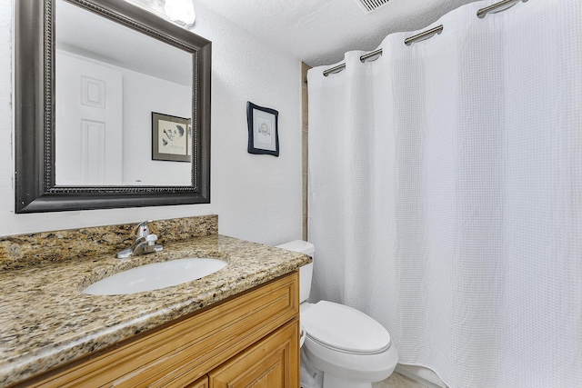 bathroom featuring vanity, toilet, and a textured ceiling