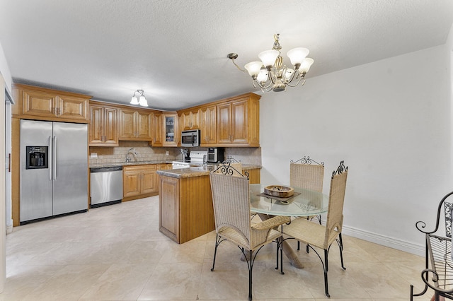 kitchen with dark stone counters, sink, decorative backsplash, appliances with stainless steel finishes, and a chandelier