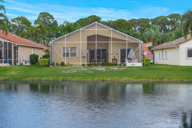 back of property featuring glass enclosure, a yard, and a water view