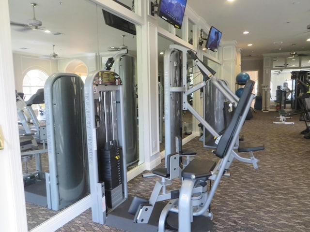 gym featuring dark colored carpet, ceiling fan, and ornamental molding