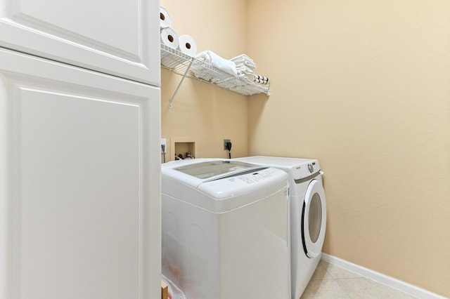 laundry area with light tile patterned floors and washing machine and clothes dryer