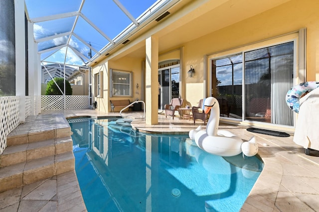 view of pool with glass enclosure and a patio area