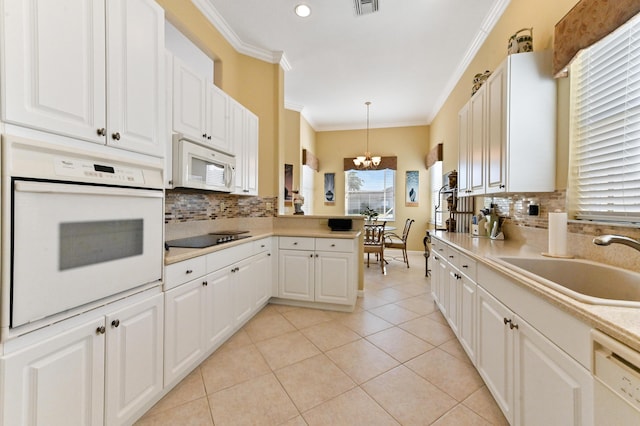 kitchen with white appliances, sink, pendant lighting, white cabinets, and ornamental molding