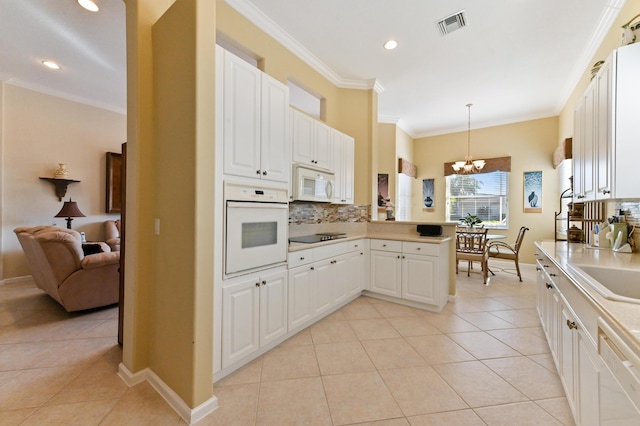 kitchen featuring white appliances, white cabinetry, crown molding, kitchen peninsula, and hanging light fixtures