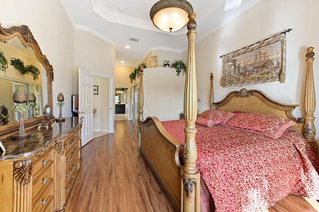 bedroom with a tray ceiling, ornamental molding, and dark wood-type flooring