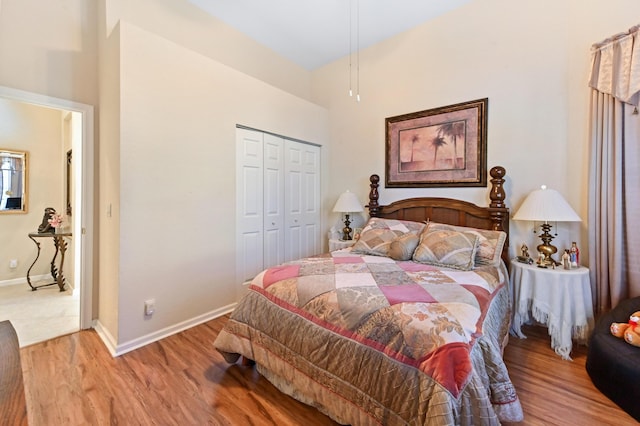 bedroom featuring a high ceiling, wood-type flooring, and a closet