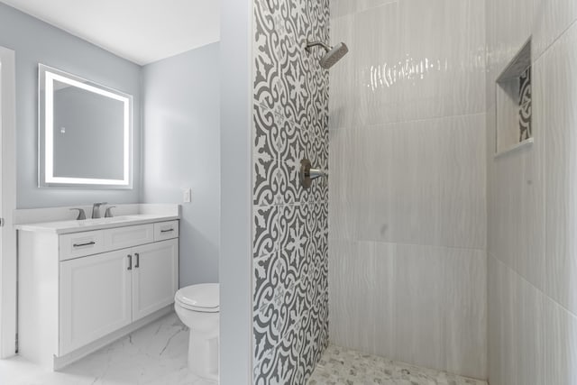 bathroom featuring toilet, vanity, and tiled shower