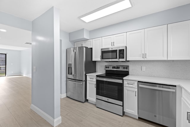 kitchen featuring white cabinets, backsplash, stainless steel appliances, and light hardwood / wood-style flooring