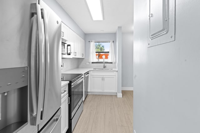 kitchen with appliances with stainless steel finishes, light wood-type flooring, tasteful backsplash, sink, and white cabinetry