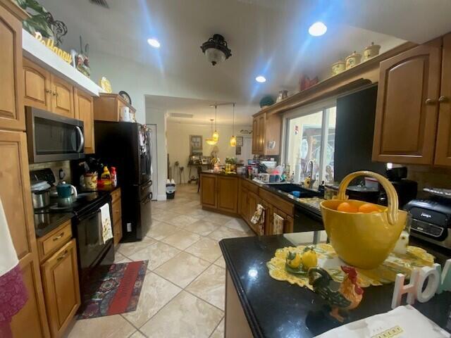 kitchen featuring black appliances, sink, vaulted ceiling, light tile patterned floors, and decorative light fixtures