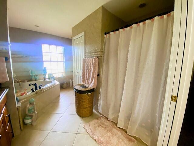 bathroom with tile patterned flooring, vanity, and a tub to relax in