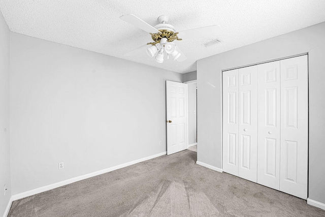 unfurnished bedroom featuring a textured ceiling, a closet, ceiling fan, and light colored carpet