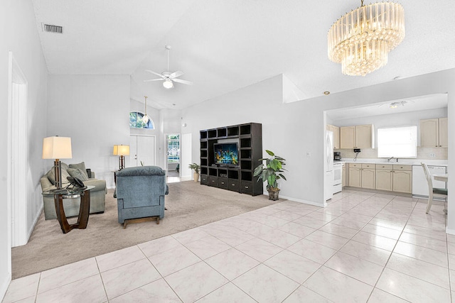 living room featuring ceiling fan with notable chandelier, a healthy amount of sunlight, light carpet, and high vaulted ceiling