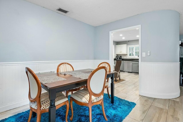 dining area with a textured ceiling and light hardwood / wood-style flooring