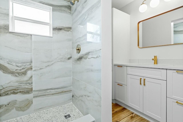 bathroom featuring tiled shower, wood-type flooring, and vanity