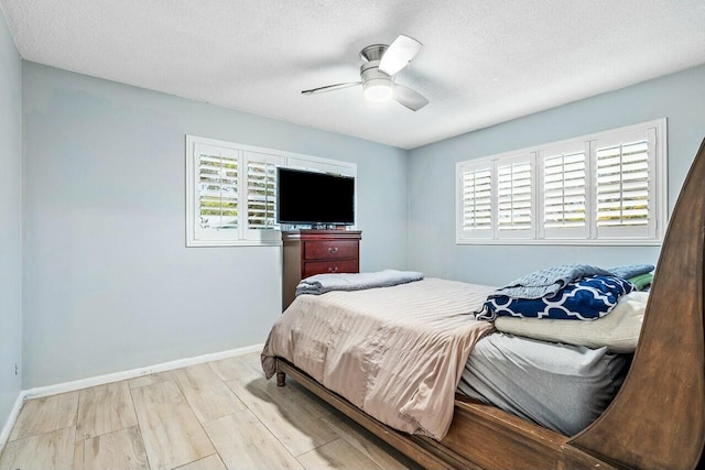 bedroom featuring ceiling fan, light wood-type flooring, a textured ceiling, and multiple windows