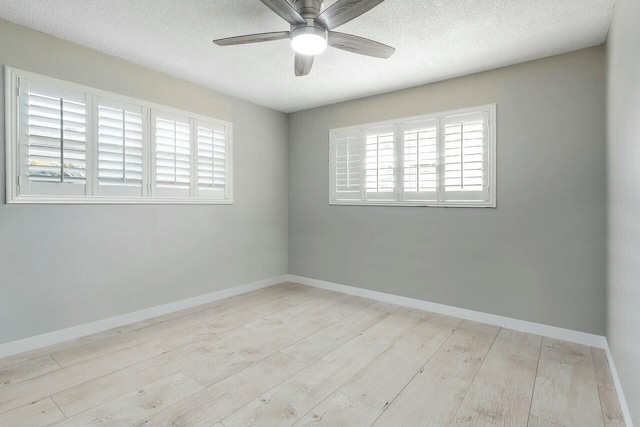 unfurnished room featuring plenty of natural light, light hardwood / wood-style floors, and a textured ceiling