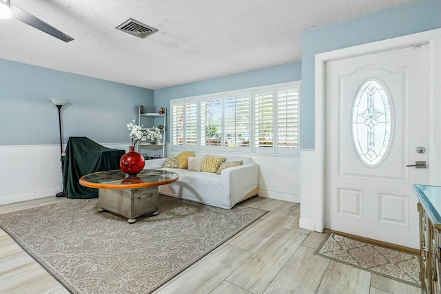 entryway with ceiling fan, a textured ceiling, and light wood-type flooring