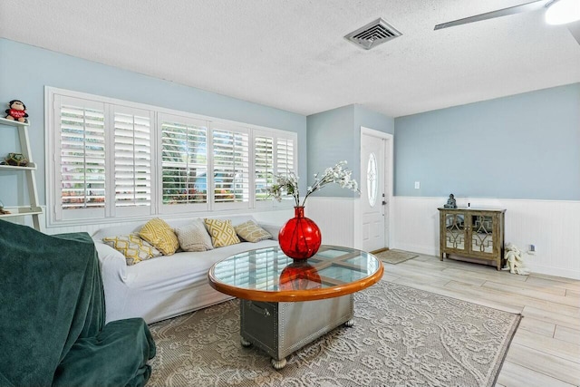 living room featuring a textured ceiling, hardwood / wood-style flooring, and a healthy amount of sunlight