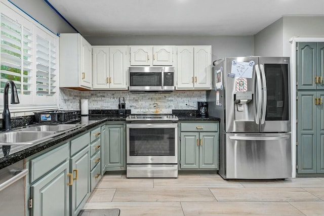 kitchen with white cabinetry, sink, dark stone countertops, decorative backsplash, and appliances with stainless steel finishes