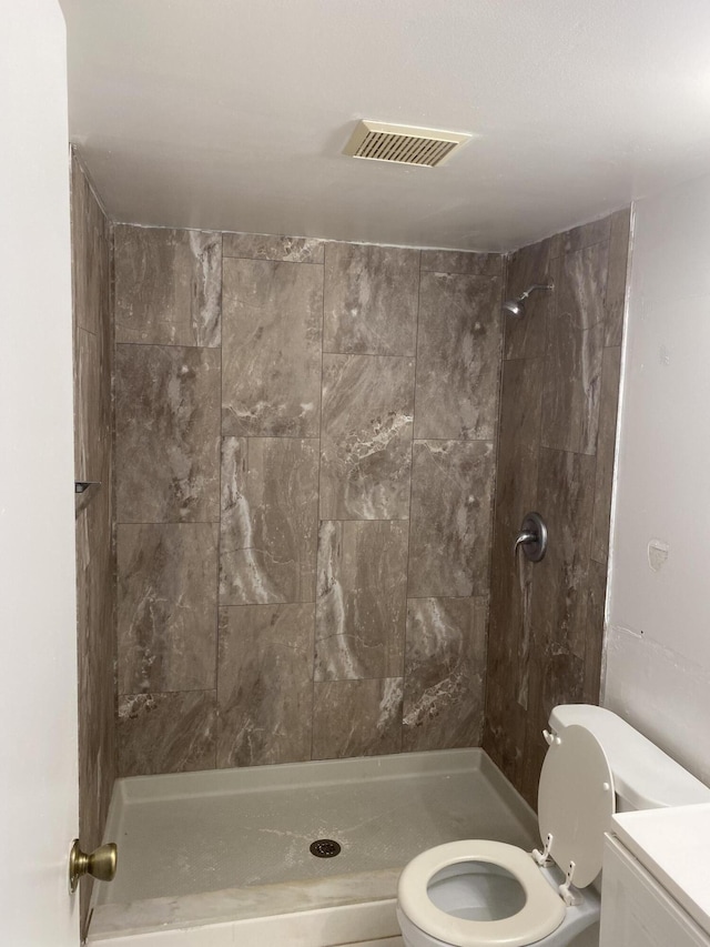 bathroom featuring tiled shower, vanity, and toilet