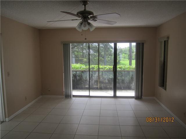 tiled spare room featuring a textured ceiling and ceiling fan